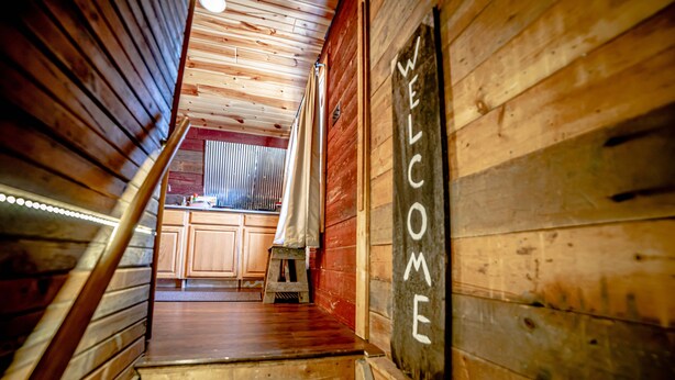A wooden staircase leading to a kitchen with a 'WELCOME' sign.