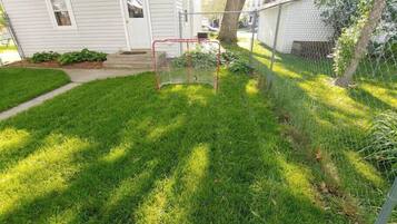 A residential yard with a fenced area, a house, and a tree.