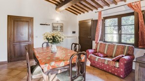 A dining area with a wooden table and chairs, a sofa, and a window with curtains. - Holiday Home in Citerna Near Castello Bufalini (Citerna)