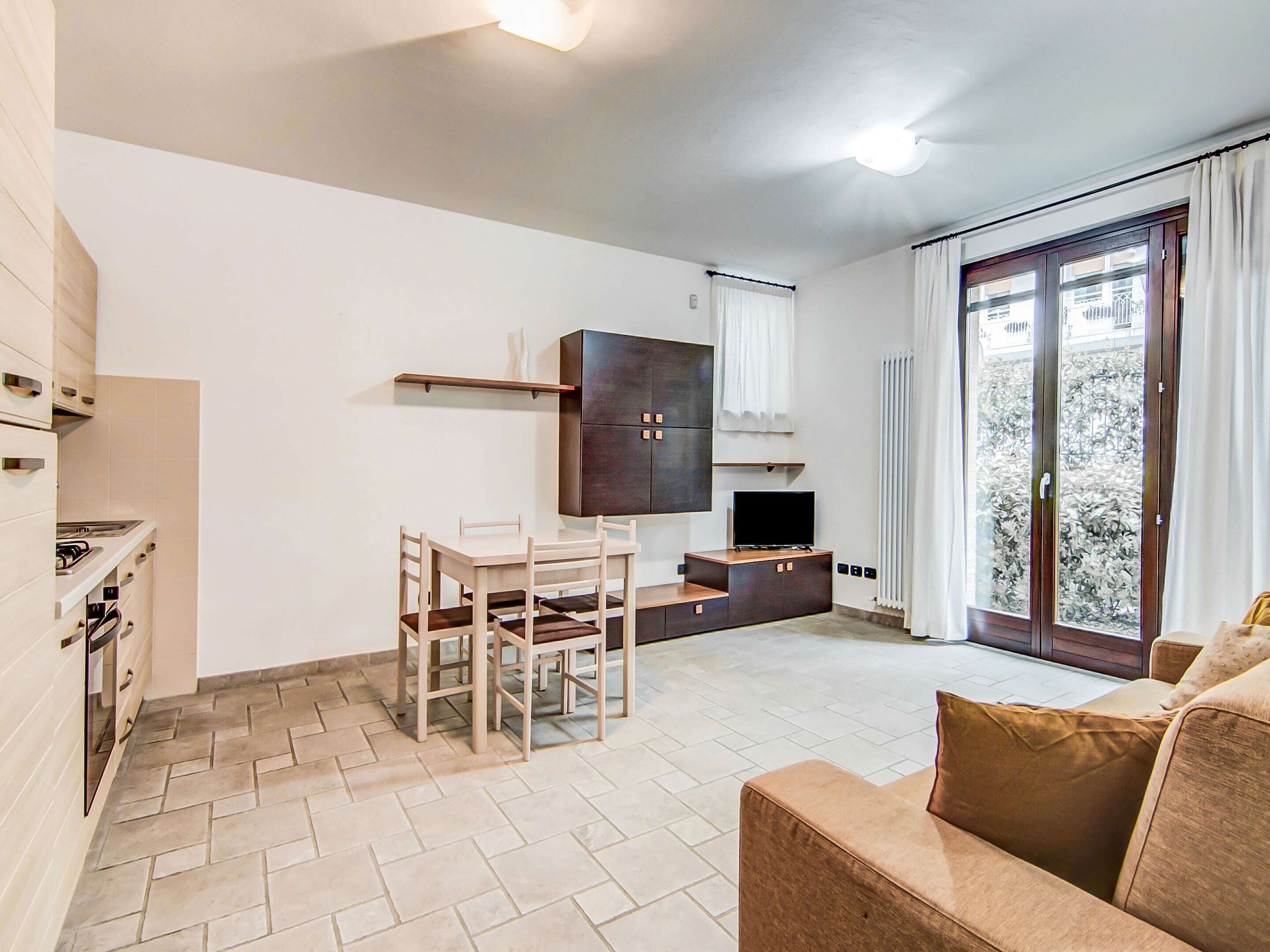 A compact living space with a kitchenette, a dining area, a sofa, and a TV.