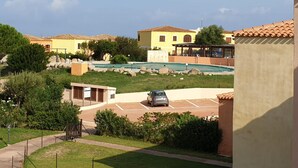 A residential area with a swimming pool, a parked car, and a building with a tiled roof. - Belvilla by OYO Sardegna Mare 616 (Trinità d'Agultu e Vignola)