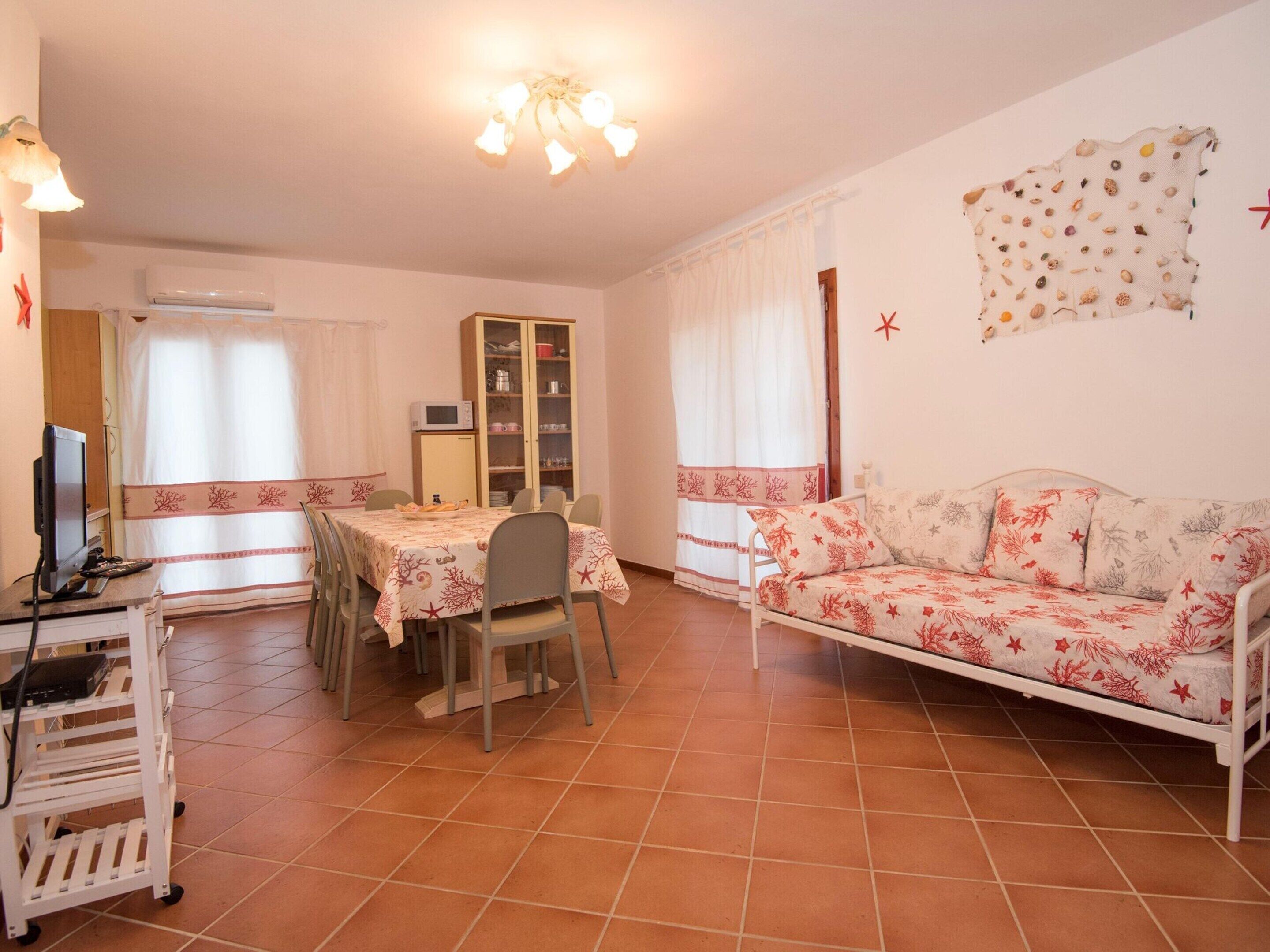 Una sala de estar con comedor, un sofá, un televisor y un aparador.