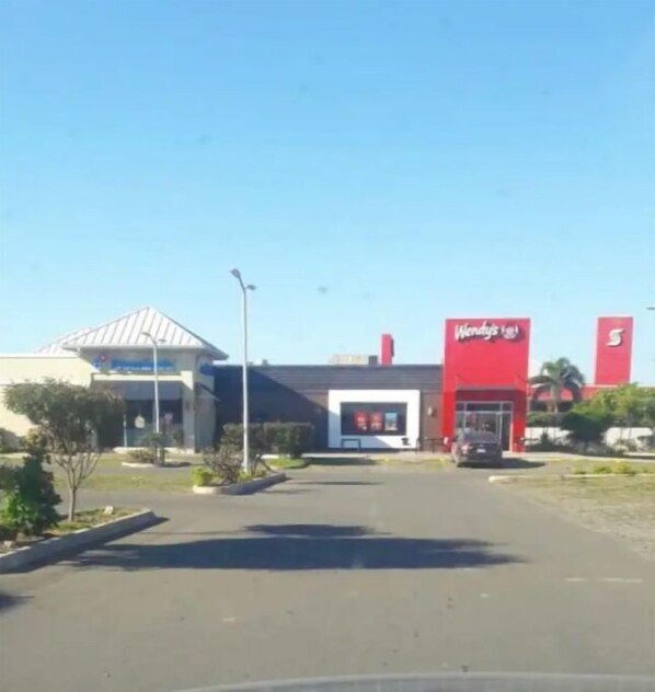 A Wendy's restaurant with a red exterior and a parking lot in front.