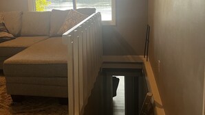 A room with a large window, a sofa, a radiator, and a staircase.