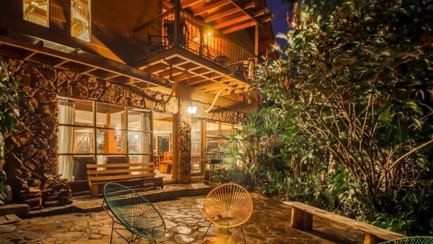 Eine Terrasse mit Steinboden, einem Feuerkorb, Sitzgelegenheiten im Freien und einem Holzdeck mit Geländer.