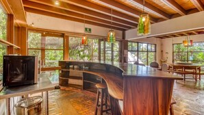 Eine moderne Küche mit einer Holzbar, großen Fenstern und hängenden Leuchten.