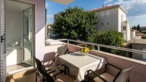 Ein Balkon mit Tisch, Stühlen und einer Obstschale.