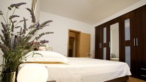 A bedroom with a bed, a bedside lamp, a vase with flowers, and a wardrobe. - Apartments Villa Grlica - One Bedroom Apartment With Terrace and Sea View (Sutivan)
