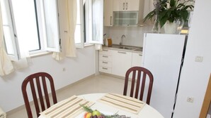 A dining area with a round table, chairs, and a fruit bowl. - Apartments Villa Grlica - One Bedroom Apartment With Terrace and Sea View (Sutivan)