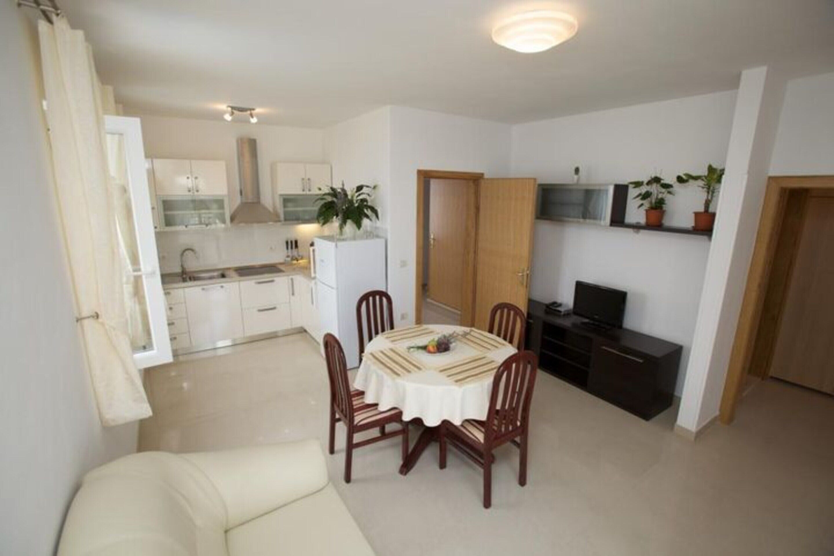 A compact living space with a dining area, kitchenette, and a television.