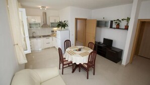 A compact living space with a dining area, kitchenette, and a television. - Apartments Villa Grlica - One Bedroom Apartment With Terrace and Sea View (Sutivan)