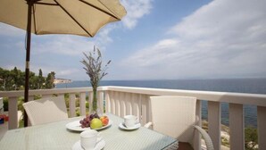 A table with a glass top, white chairs, a beige umbrella, and a view of the sea. - Apartments Villa Grlica - One Bedroom Apartment With Terrace and Sea View (Sutivan)