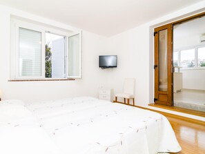 A bedroom with a bed, a TV, a chair, and a sliding door to a balcony. - Apartments Nikola - One Bedroom Apartment With Terrace and Garden View (Dubrovnik)
