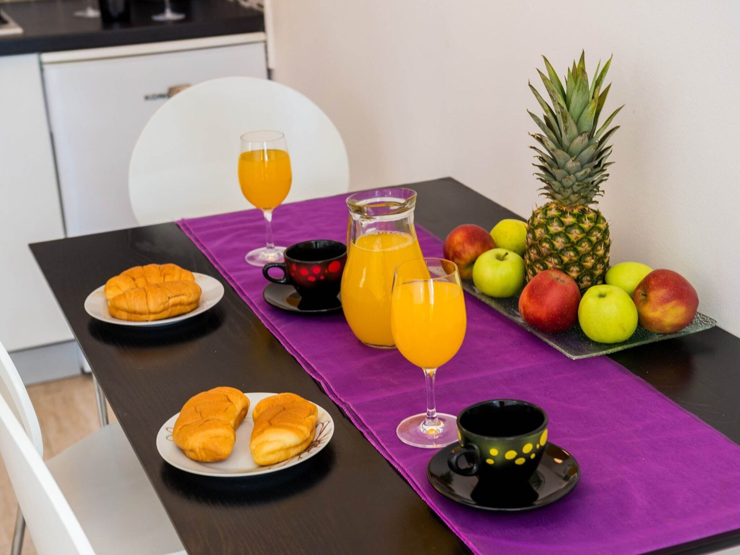 Ein Frühstückstisch mit Croissants, Saft und Obst.