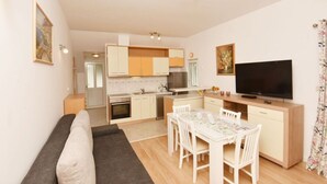 A compact living space with a kitchenette, a dining area, and a television. - Green Hills Apartment - One Bedroom Apartment With Balcony and Sea View (Dubrovnik)