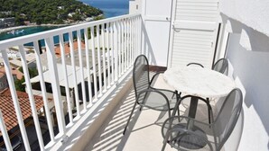 A balcony with a white railing, a small round table, and two chairs. - Green Hills Apartment - One Bedroom Apartment With Balcony and Sea View (Dubrovnik)