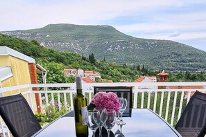 Mesa lista para comer, con una botella y vasos, con vistas a un paisaje montañoso.