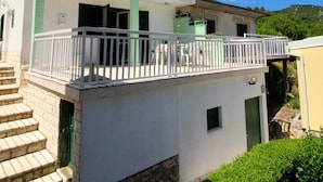 Ein zweistöckiges Gebäude mit Balkon, Treppe und einem kleinen Fenster.