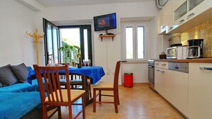 A compact kitchen with a dining area, a TV mounted above the counter, and a view of the outdoors through a window. - Apartment Mambo , Mljet - Duplex Apartment With Terrace and Sea View (Mljet)