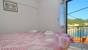 A bedroom with a bed, a view of a balcony, and a painting on the wall. - Apartment Mambo , Mljet - Duplex Apartment With Terrace and Sea View (Mljet)