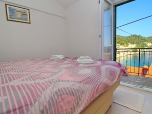 A bedroom with a bed, a view of a balcony, and a painting on the wall. - Apartment Mambo , Mljet - Duplex Apartment With Terrace and Sea View (Mljet)