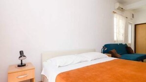 A bedroom with a bed, a bedside table with a lamp, a chair, and a window with curtains. - Apartments Felix Mljet - One Bedroom Apartment With Balcony (Mljet)