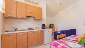 A compact kitchen with wooden cabinets, a built-in stove, and a white refrigerator. - Apartment in Premantura With Seaview Balcony (Medulin)