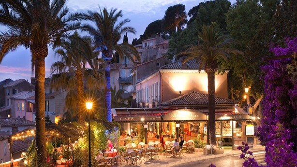 A restaurant with outdoor seating, palm trees, and a street view. - Apartment in Premantura With Seaview Balcony (Medulin)