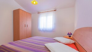 A bedroom with a bed, a nightstand, a lamp, a wardrobe, and a window with curtains. - Apartment in Premantura With Seaview Balcony (Medulin)