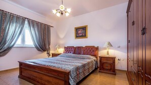 Un dormitorio con cama de madera, candelabro, mesita de noche, armario y un cuadro en la pared.