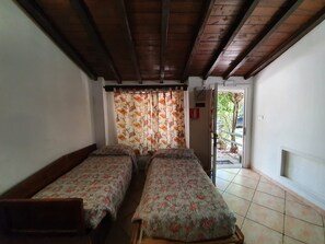 A room with two single beds, wooden beams on the ceiling, a floral curtain, and a tiled floor. - Belvilla by OYO Veio 4 pax (Rome)