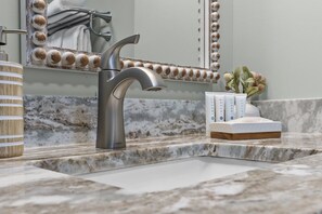 A bathroom with a modern sink, a mirror with decorative beads, and a wooden vanity.