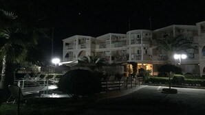 Un hôtel à plusieurs étages doté de balcons, d’une piscine et de palmiers.