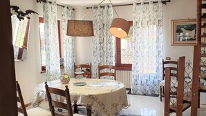 A dining area with a round table, chairs, a vase, and curtains. - Vesime Villa With Garden (Vesime)