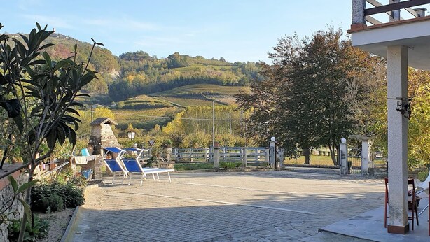 A paved outdoor area with lounge chairs and a stone wall. - Vesime Villa With Garden (Vesime)