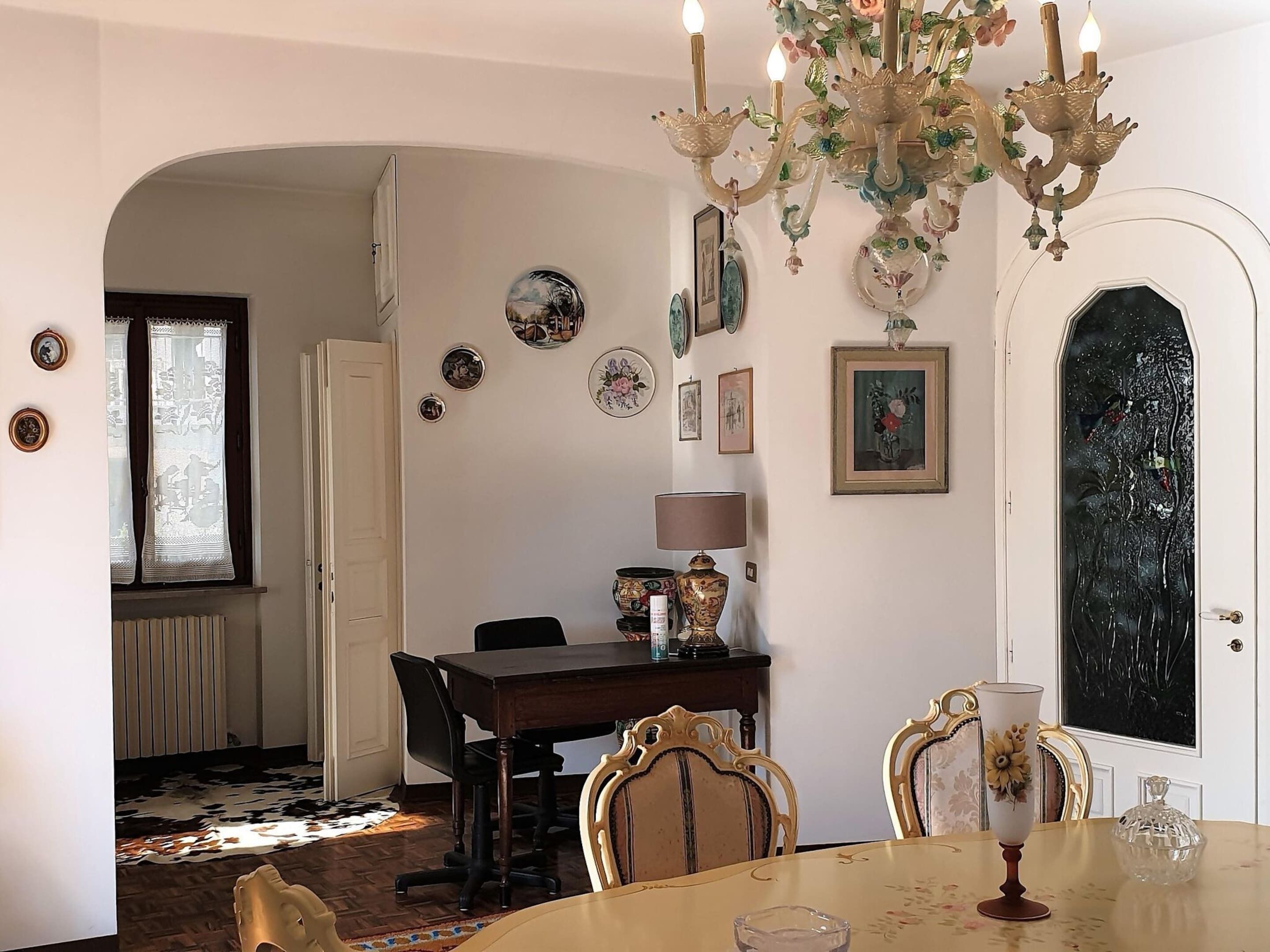 A dining area with a chandelier, a table with chairs, and a door with a decorative glass panel.