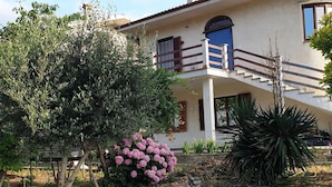 A two-story house with a balcony, a stone staircase, and a garden with various plants and flowers. - Vesime Villa With Garden (Vesime)