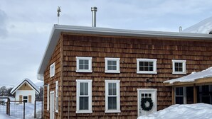 A two-story wooden house with white trim, a front door, and a wreath on the door. - Darling Cottage Close to Resorts and other winter activities. (Eden)