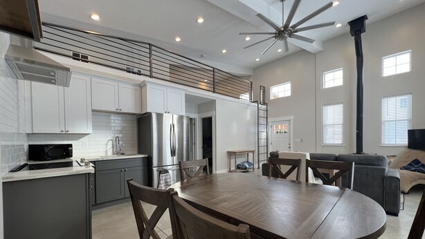 A modern kitchen with white cabinets, stainless steel appliances, and a dining area with a wooden table and chairs. - Darling Cottage Close to Resorts and other winter activities. (Eden)