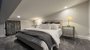 A bedroom with a bed, two bedside tables, a lamp, and a wall-mounted outlet. - Darling Cottage Close to Resorts and other winter activities. (Eden)