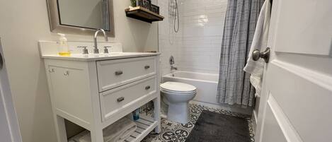 Une salle de bain avec un meuble-lavabo blanc, des toilettes, une douche et un carrelage décoré.