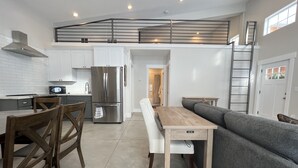 A modern kitchen with white cabinets, a stainless steel refrigerator, and a dining area with a wooden table and chairs. - Darling Cottage Close to Resorts and other winter activities. (Eden)