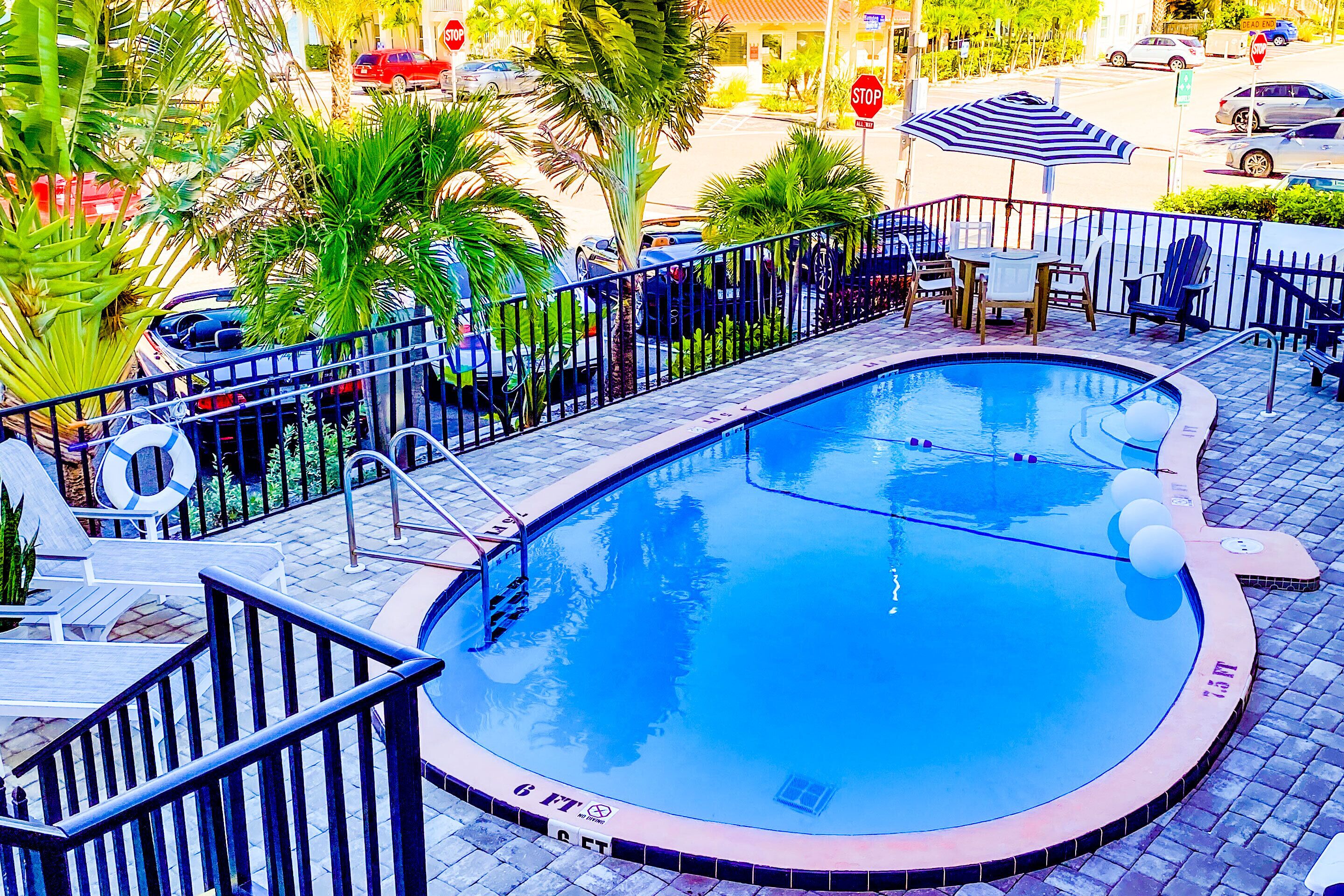 A swimming pool with a curved edge, surrounded by a metal fence, and a lifebuoy attached to the fence.