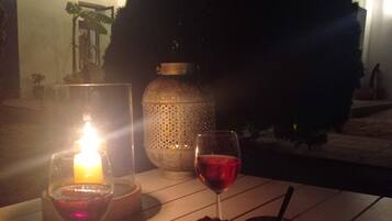 Un área de comedor al aire libre con una mesa iluminada por velas, copas de vino y un postre.