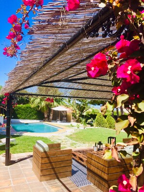 A poolside area with a pergola, outdoor furniture, and a view of a swimming pool and garden. - Villa Pinos Malaga (Alhaurin de la Torre)