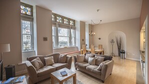 Ein Wohnzimmer mit zwei Sofas, einem Couchtisch und einem großen Fenster mit Buntglas.