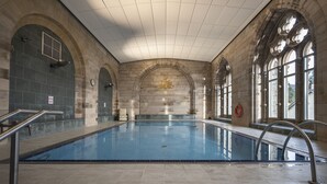Ein Hallenbad mit Steinwänden und Rundbogenfenstern.