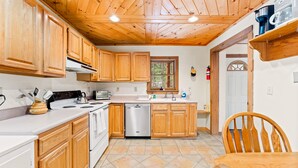 Una cocina con armarios de madera, lavavajillas de acero inoxidable y encimera blanca.