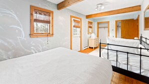 Un dormitorio con cama, vigas de madera, cómoda y espejo.