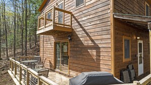 Una cabaña de madera con terraza, mobiliario exterior y zona de barbacoa.